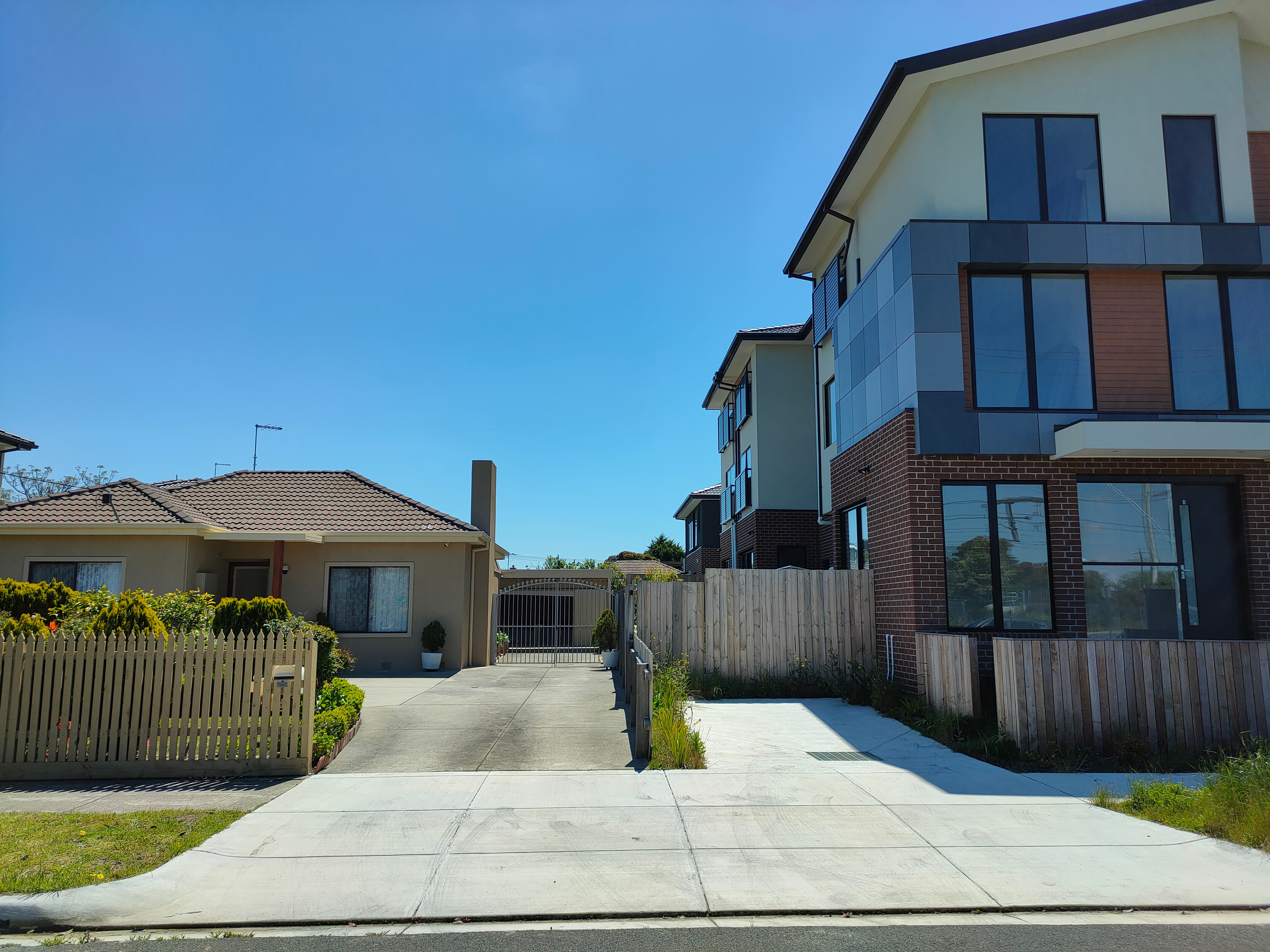 An old one floor house next to a three-storey structure.