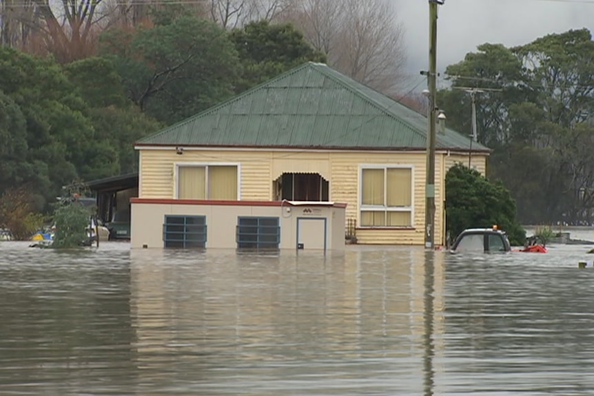 A house is submerged in floodwaters. The second story can be seen.