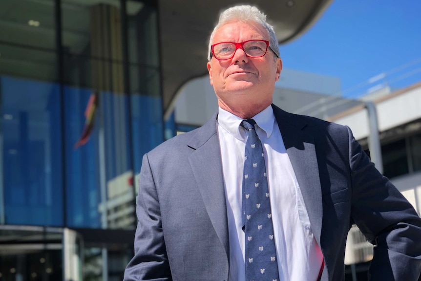 David McBride, wearing red glasses and looking off into the distance, outside the ACT court precinct.