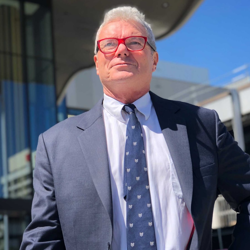 David McBride, wearing red glasses and looking off into the distance, outside the ACT court precinct.