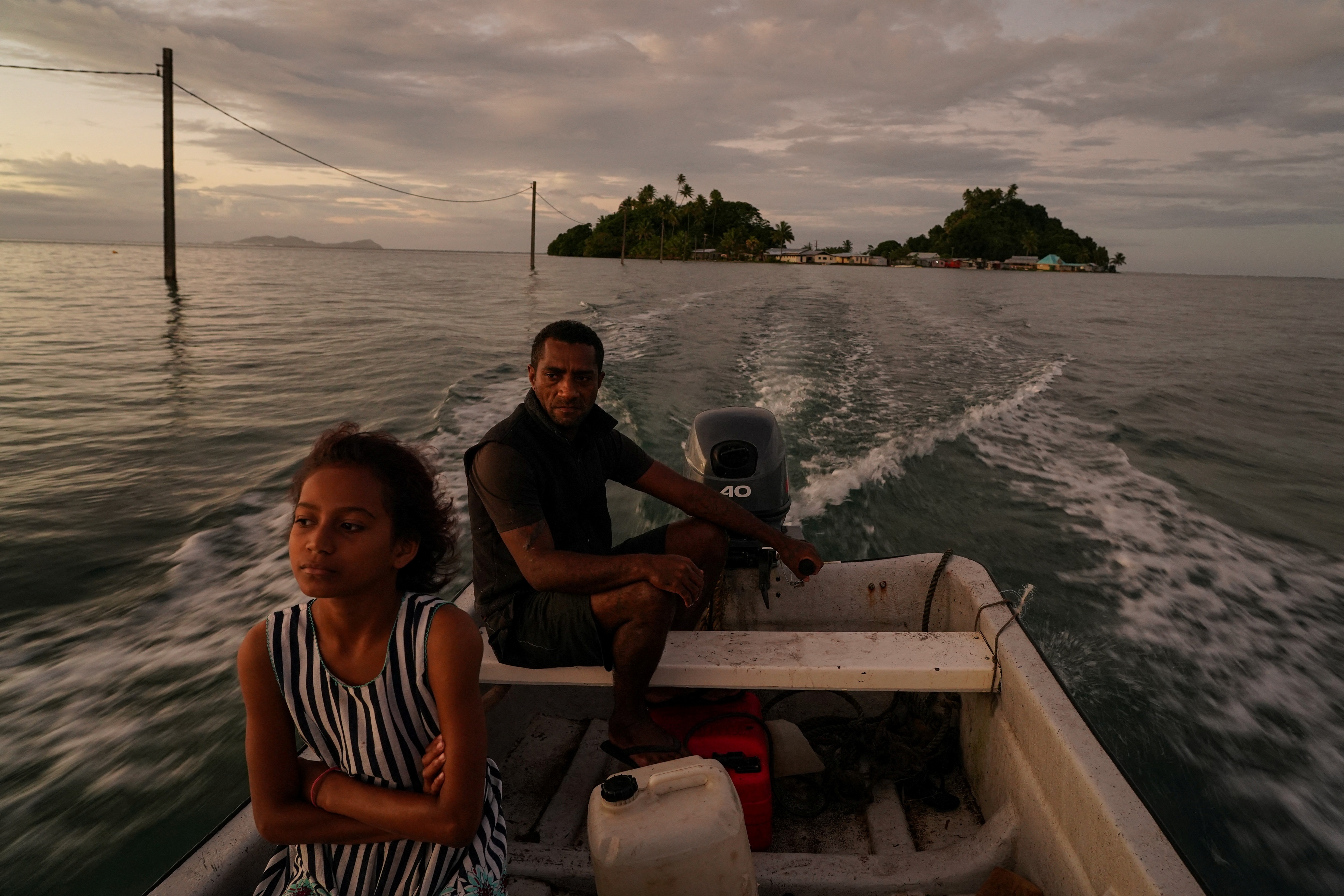 A man and child in a motorboat off the shore of a small Fijian island
