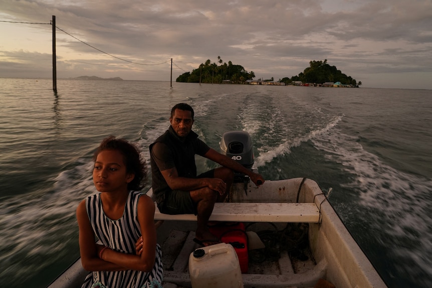A man and child in a motor boat off the shore of a small island in Fiji