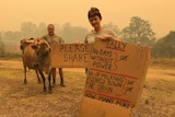 A man an d woman stand in smoke holding a sign