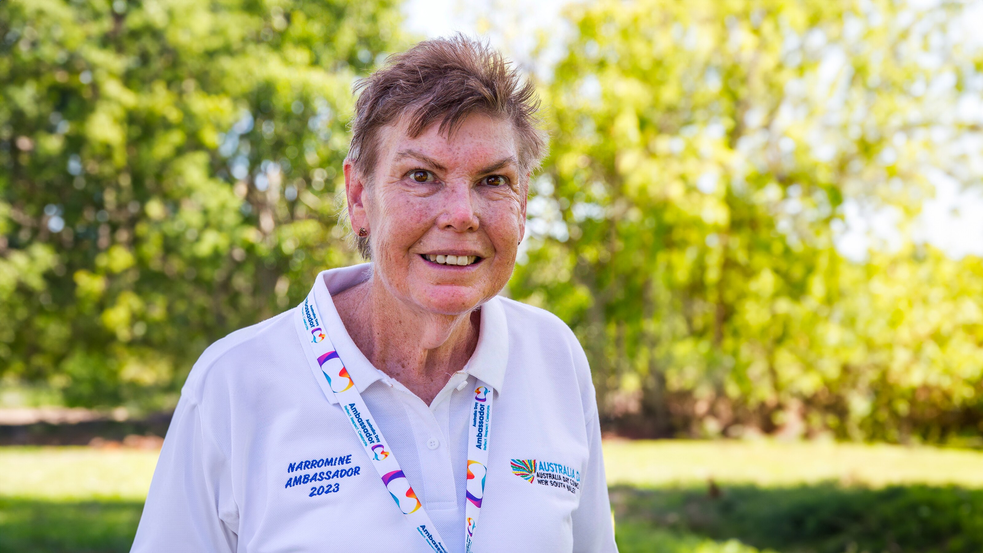 A woman stands smiling at a camera