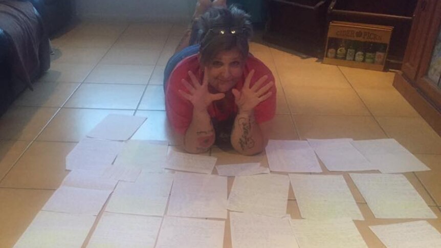 A woman lies on the ground surrounded by many pieces of paper