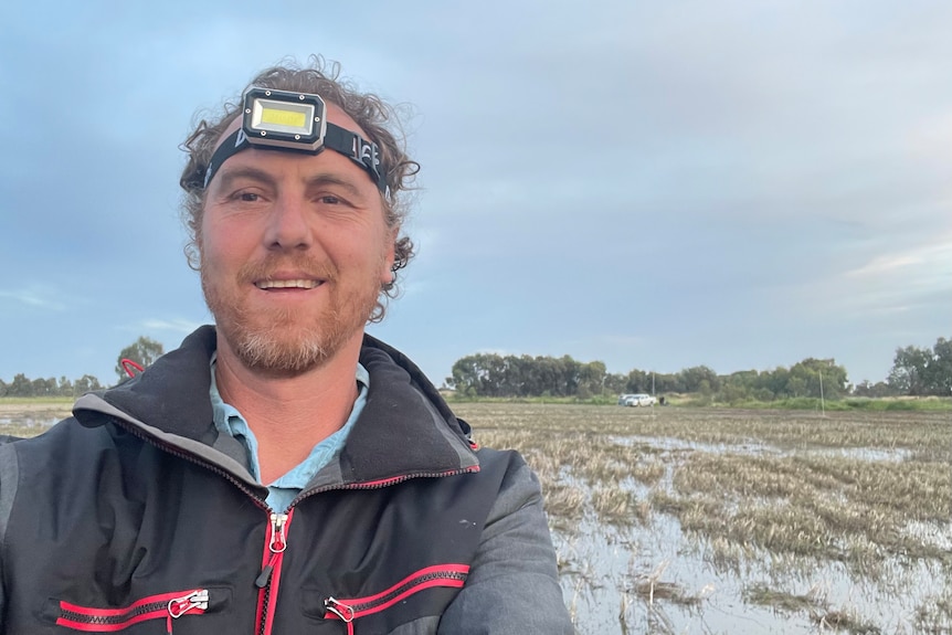 A selfie of ecologist Matt Herring wearing a head lamp and rain jacket in Riverina wetlands.