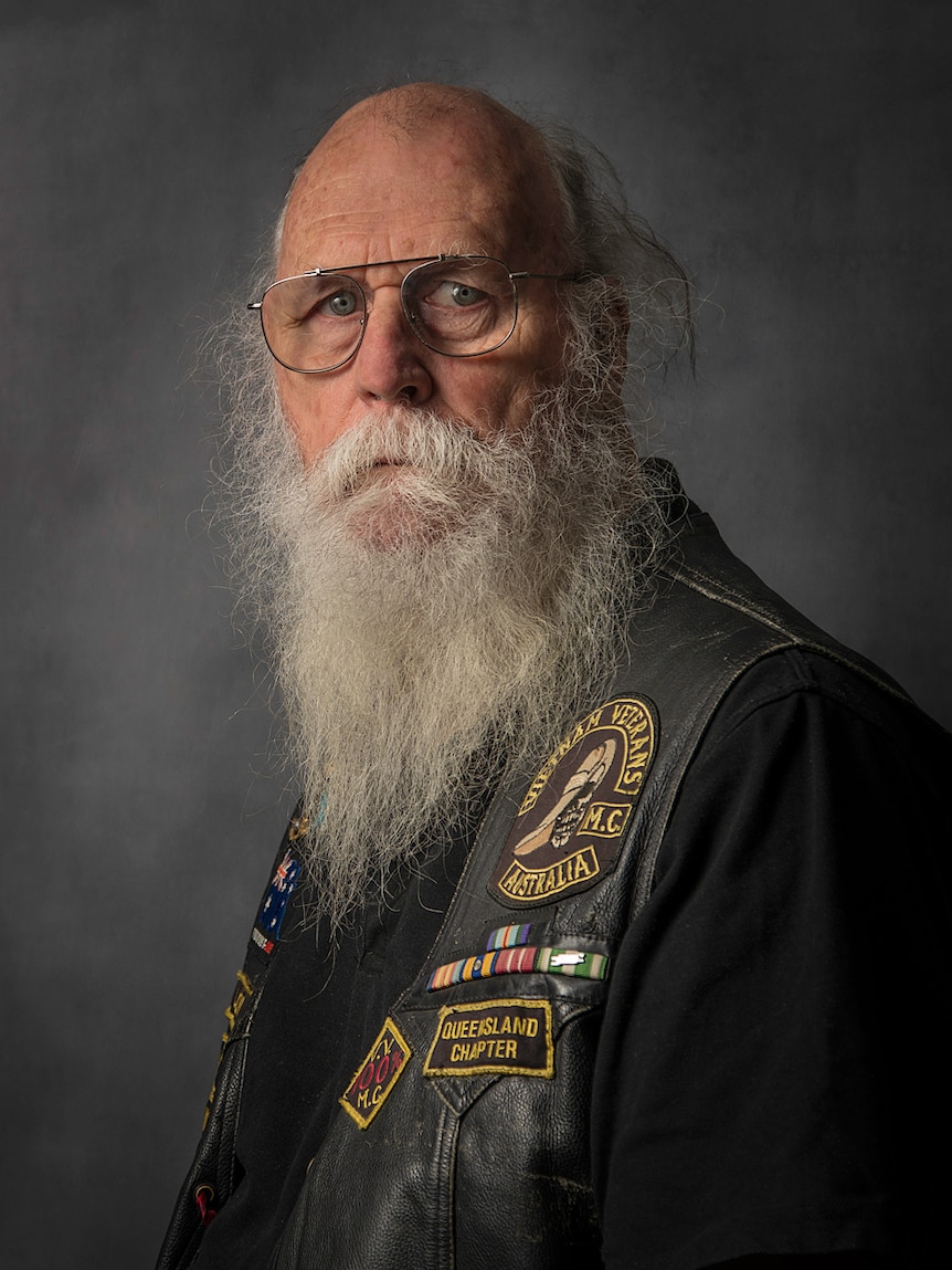 A man with glasses and a bi white beard wearing a leather motorcycle vest