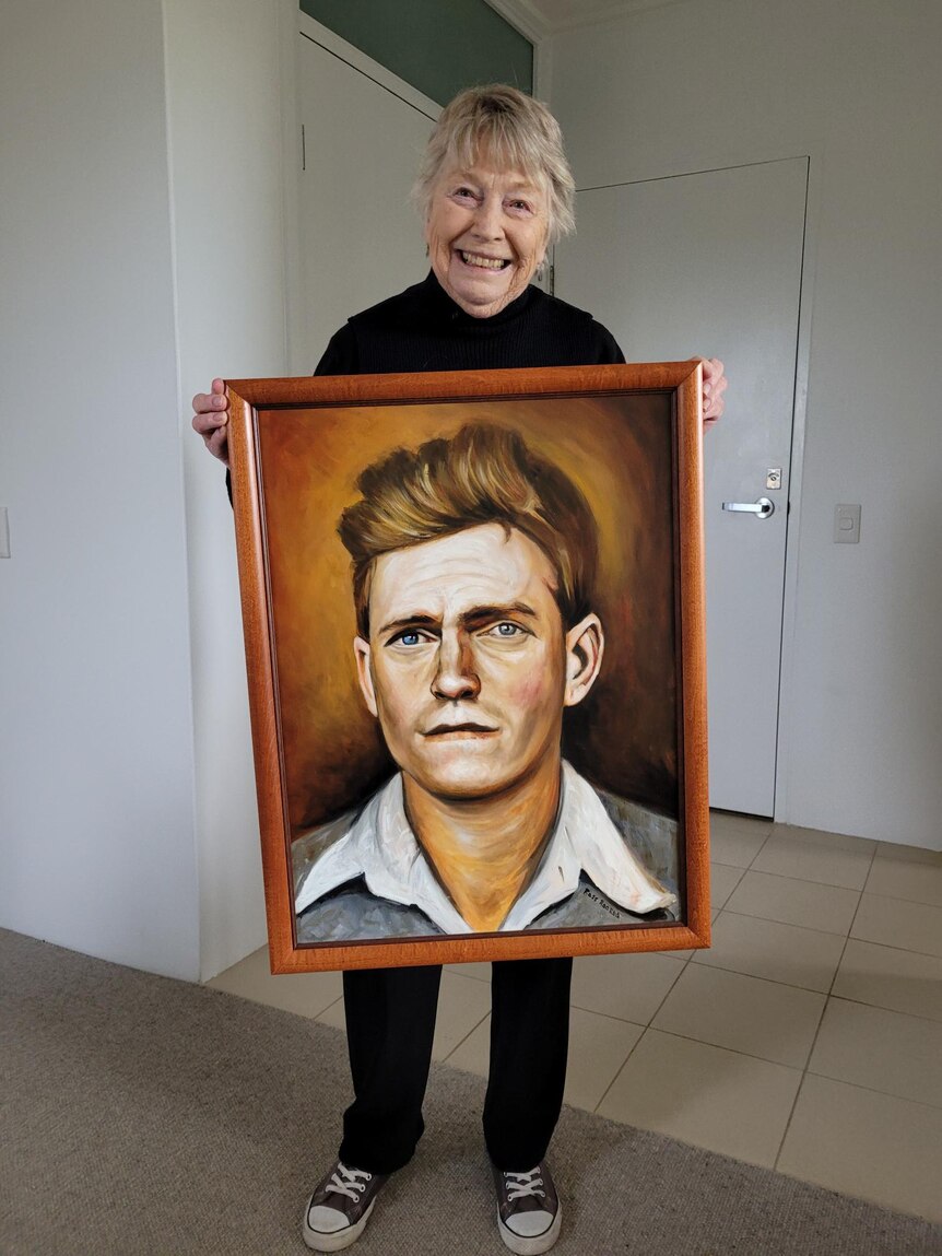 Wendy holds a colourful portrait of Harry Frank in his twenties.