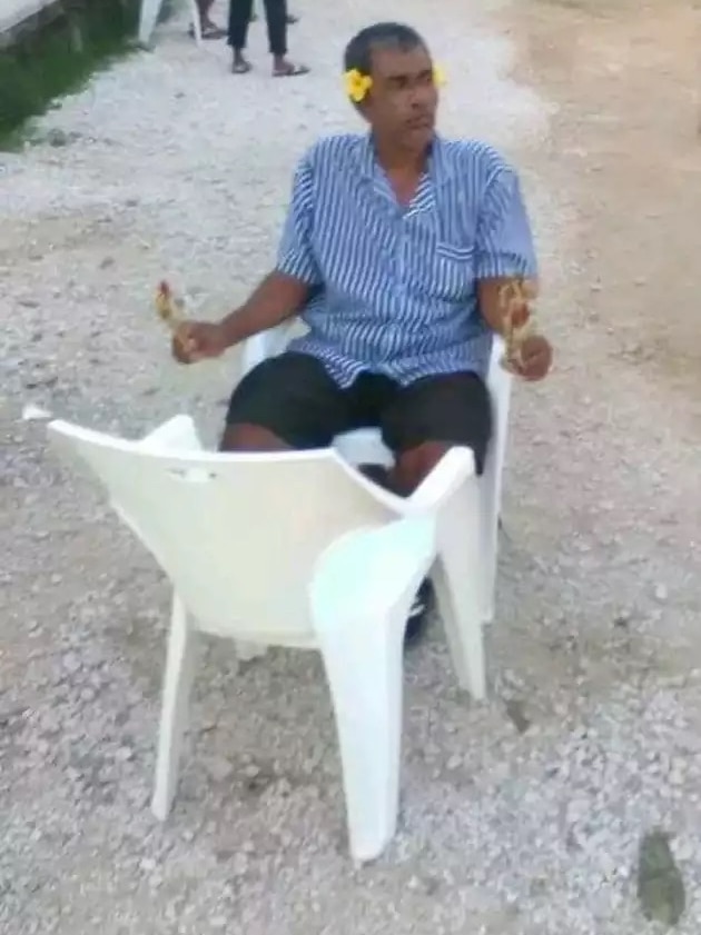 Salim Kyawning sits with yellow flowers behind his ears and small bunches in his hands.