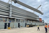 Wind turbine blades being unloaded at a wharf.