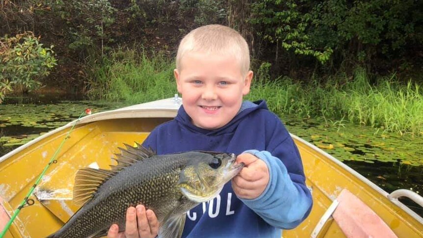 Young fisherman Fraser Prentice proudly holds a fish caught in the family's much loved tinny