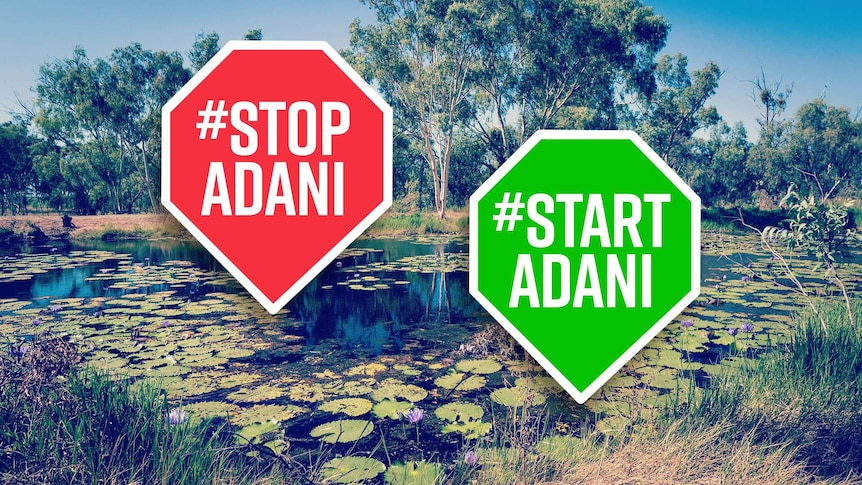 A #Stop Adani and #Start Adani sign and in the background, water with lilies and native Australian bushland.