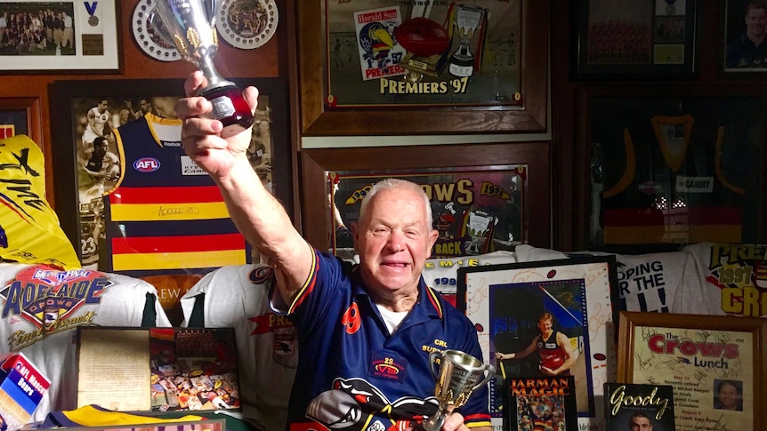 A man sits in his home surrounded by Adelaide Crows memorabilia