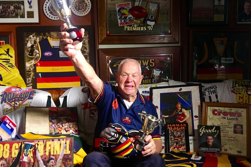 A man sits in his home surrounded by Adelaide Crows memorabilia