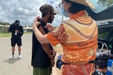Young Aboriginal man gets vaccinated by health worker on a street in Cherbourg.