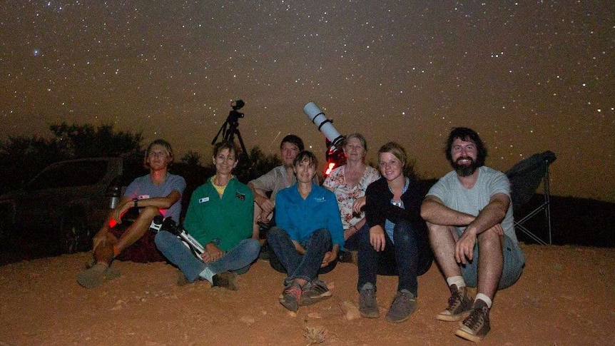A group of people on a hill at night.