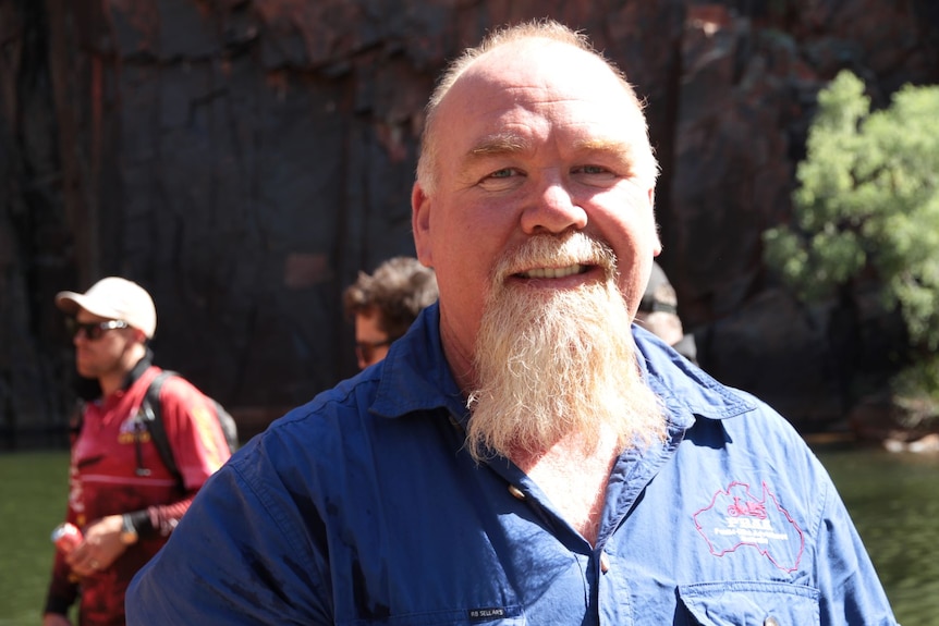 a man with a beard stands among other men in a gorge