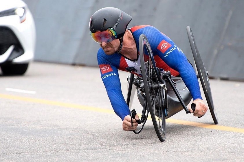 A paracyclist turns the pedals of his bike with his hands during a race. 