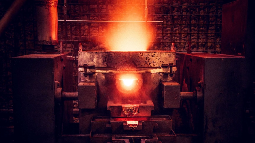 Furnace pours hot gold metal at gold mine