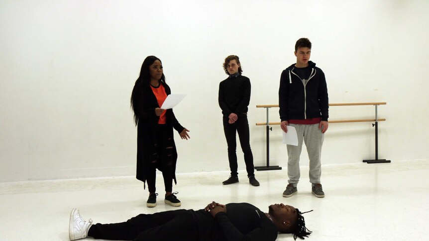 A group of young people rehearsing a play in a white room