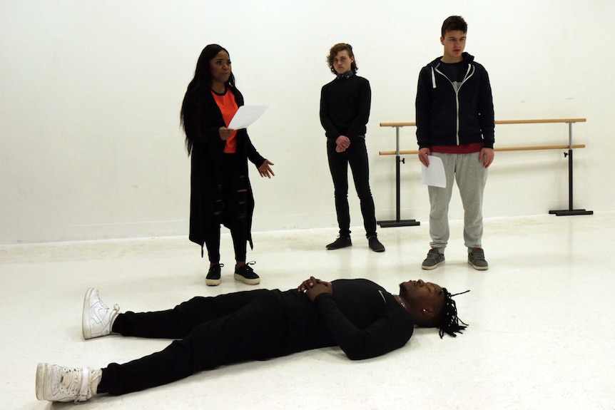 A group of young people rehearsing a play in a white room