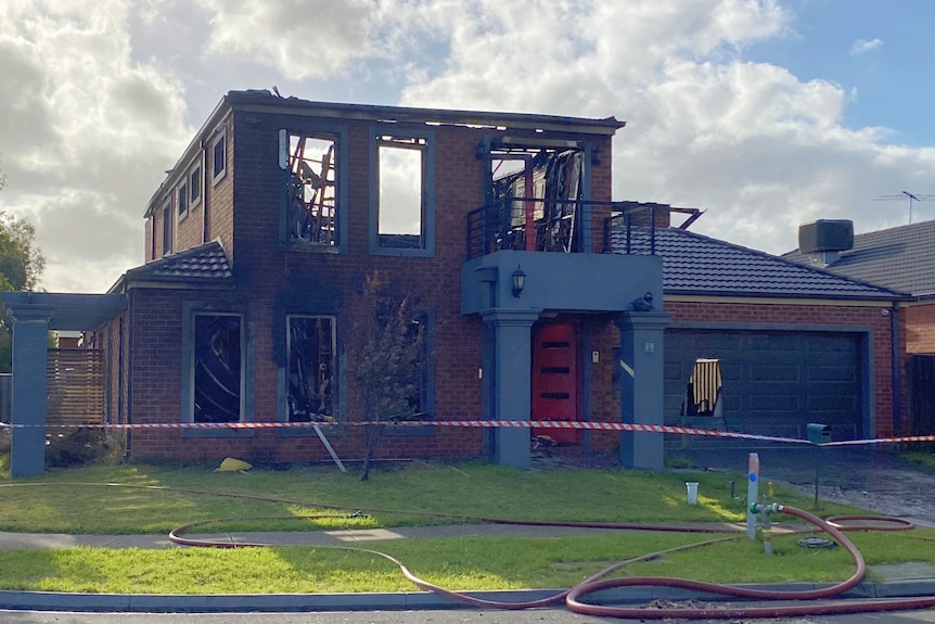 A burnt house with a fire house in front of it.