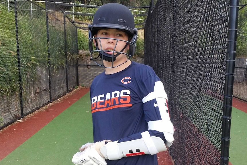 Cooper stands next to cricket nets.