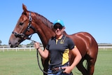 A young woman Mareeba Trainer standing outside with racehorse Regal Heart