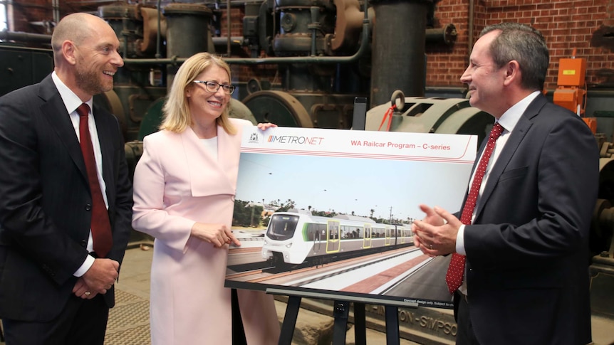 Mark Coxon, Rita Saffioti and Mark McGowan stand around a picture of a railcar smiling at each other and posing for a photo.