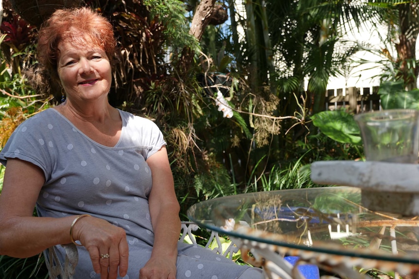 A woman sitting in her garden beside a glass table