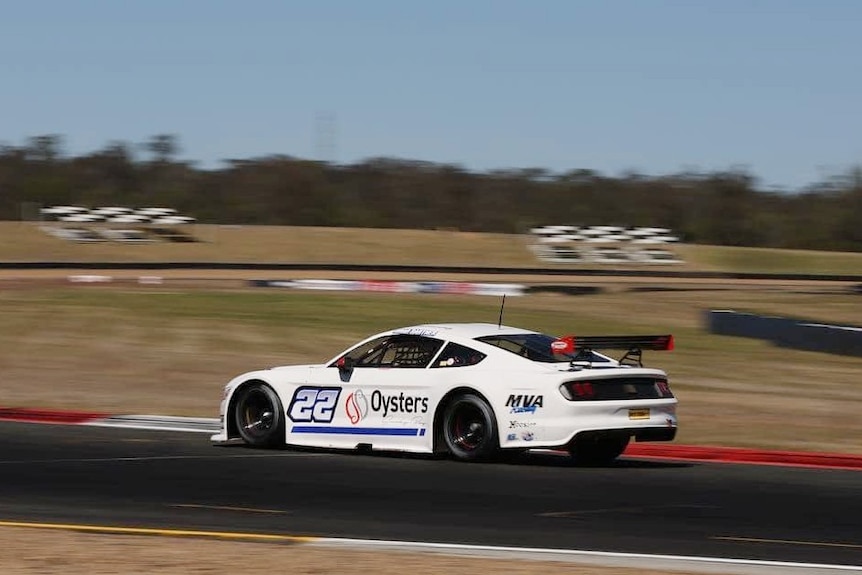 A white racing car in action on the race track
