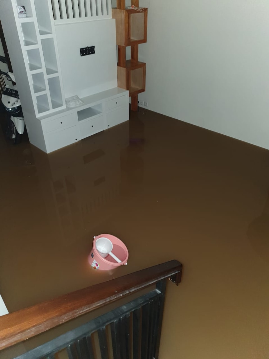 Muddy brown water flooding a ground level, picture taken from staircase.