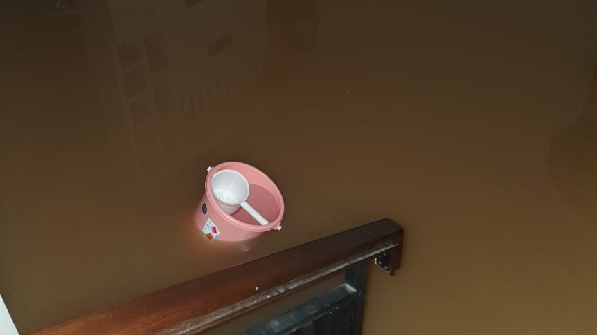 Muddy brown water flooding a ground level, picture taken from staircase.