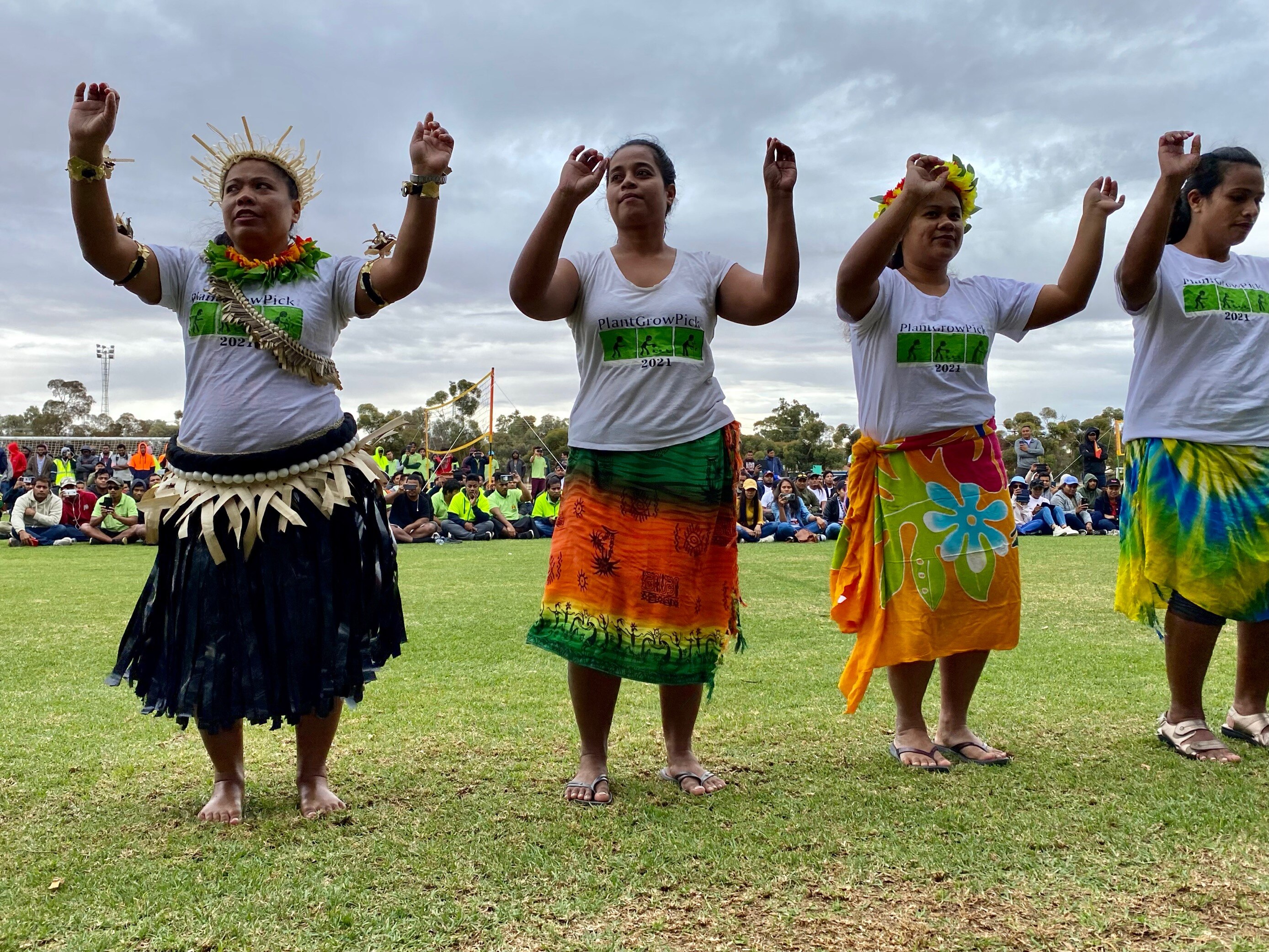 Four women in islander clothes performing a traditional dance, their arms uplifted