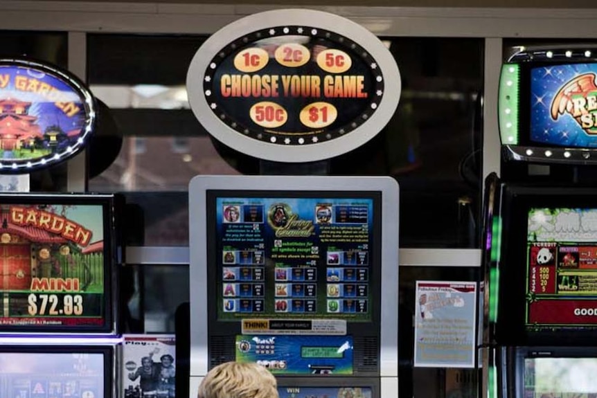 A woman plays a poker machine.