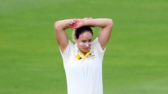 Ellyse Perry looks frustrated as she rests both arms on her head.