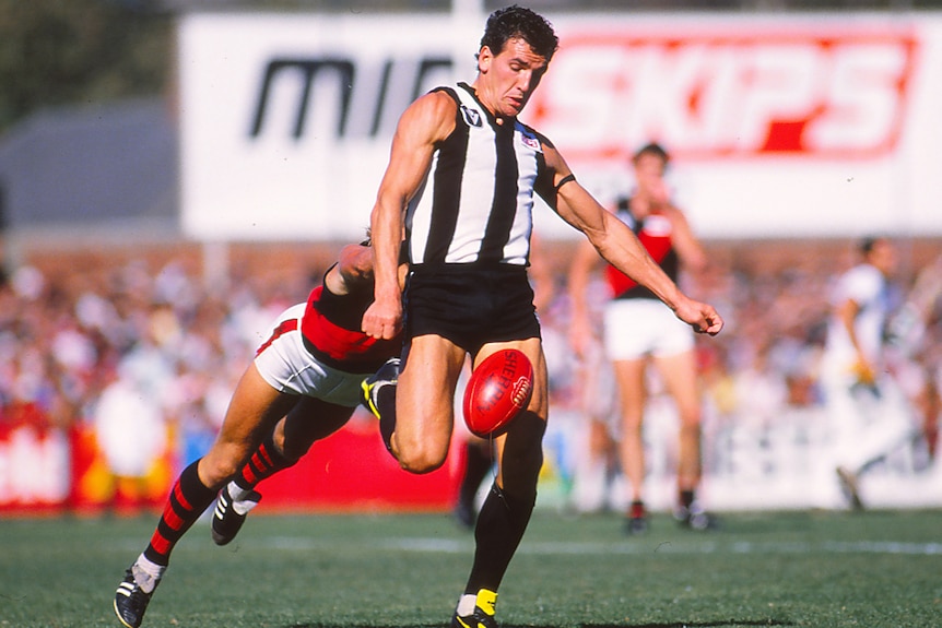 A photo from 1986 of a Collingwood VFL player kicking the ball against Essendon.