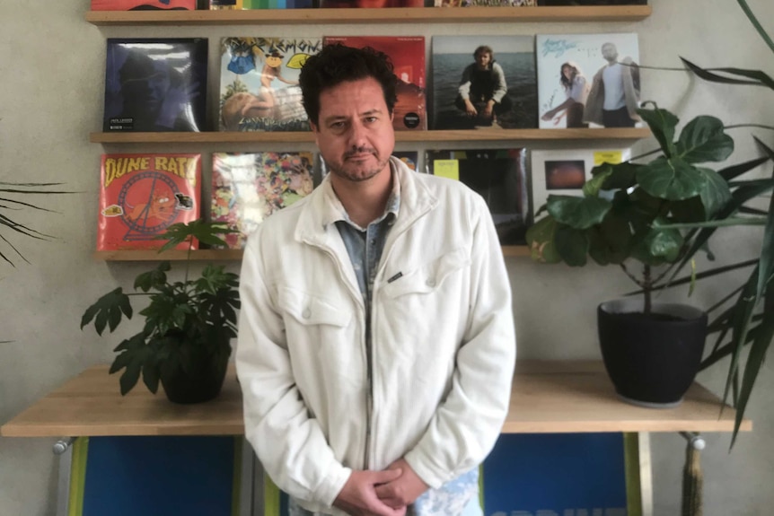 Tim Everist poses for a photo in front of a number of album covers.