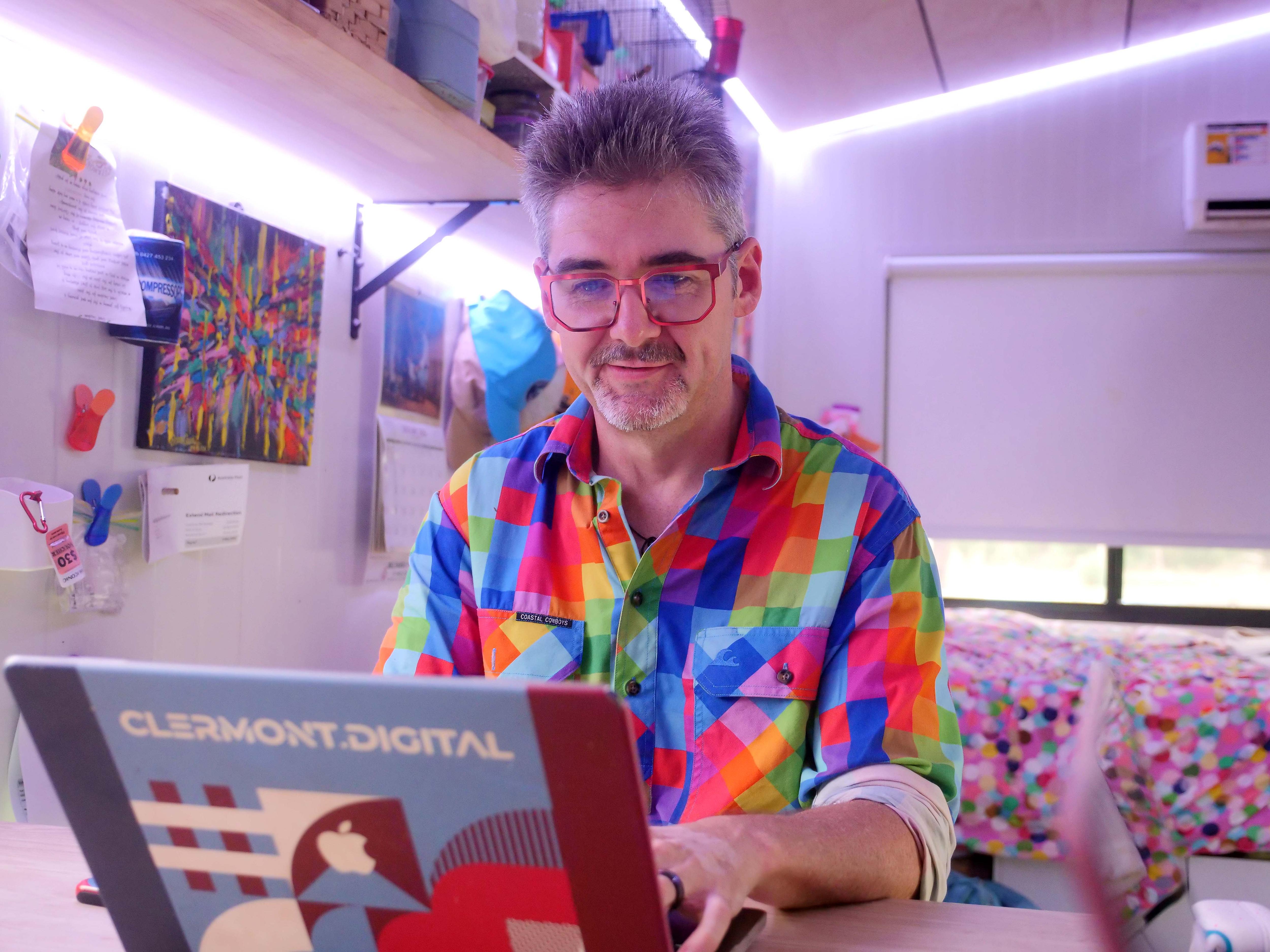 Un hombre con una camisa colorida trabaja en una computadora para crear el sitio web Gauge Weather.