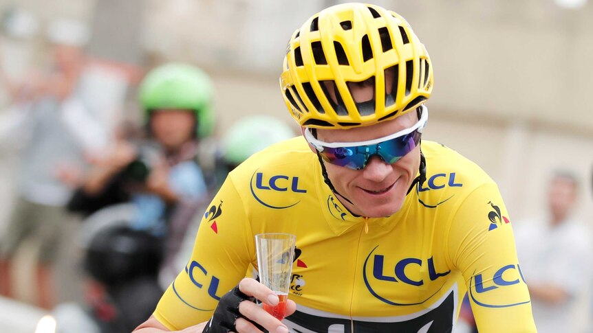 Team Sky rider and yellow jersey Chris Froome of Britain holds a glass of champagne.