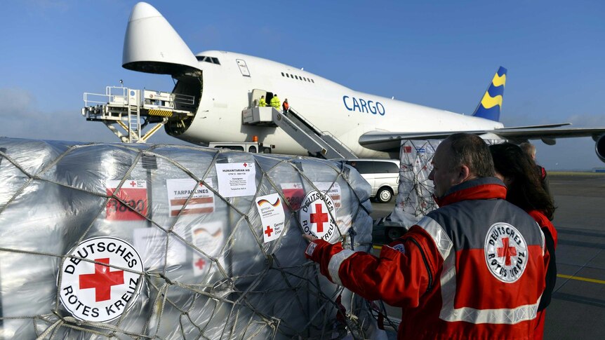 The German Red Cross and relief organisation, THW, load aid packages into an aircraft.
