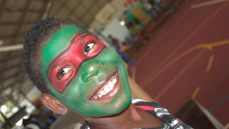 A young boy smiling at the camera with his face painting in Mapoon on Australia Day