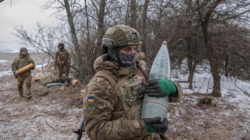 A Ukrainian serviceman carries a shell for a howitzer.