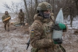 A Ukrainian serviceman carries a shell for a howitzer.