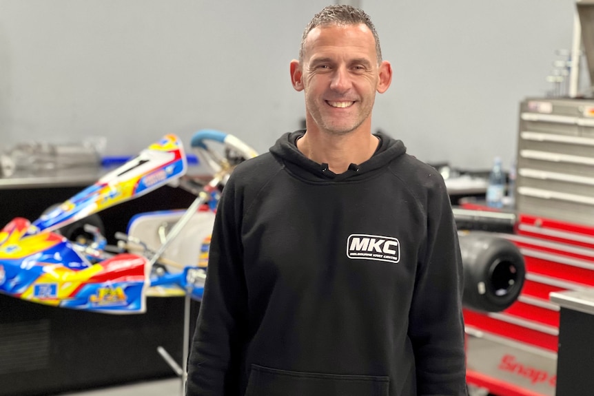 A man standing in front of a go-kart.