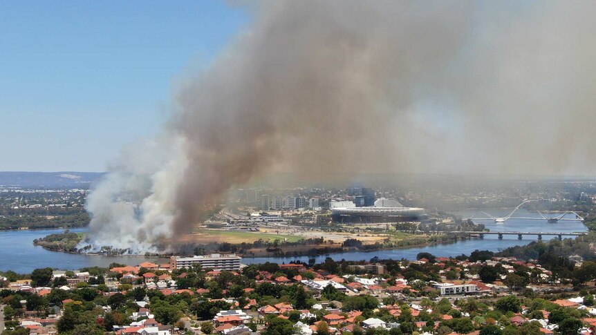 An aerial shot of Perth Stadium with a fire burning nearby.