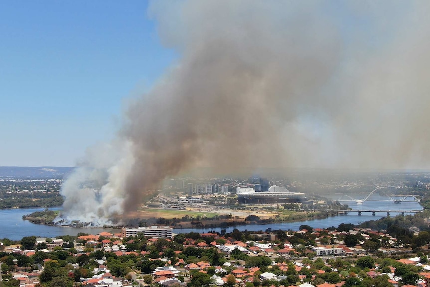 An aerial shot of Perth Stadium with a fire burning nearby.
