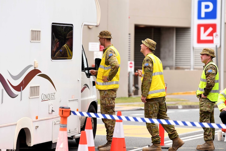 Three ADF officers talk to the driver of a caravan.