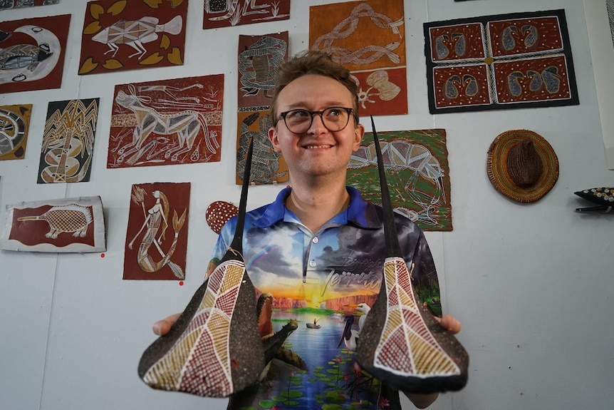 Alex Ressel from Injalak Arts holds two stingrays made out of palm fronds.