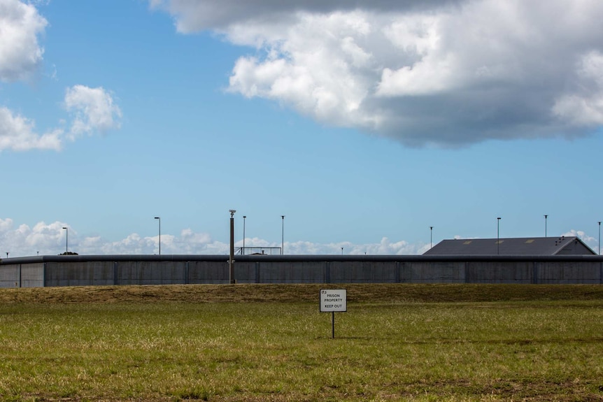 A sign reads 'PRISON PROPERTY KEEP OUT' in front of walls surrounding Port Phillip Prison.